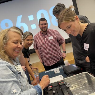 Team members collaborate and strategize with smiles during the Beat The Box team building event, unlocking new challenges as the clock counts down. thumbnail