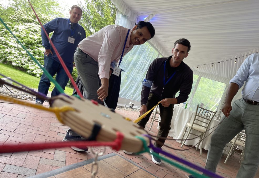 Participants working together in the Integrity team building event, using colorful ropes to complete a physical challenge while focusing on collaboration.