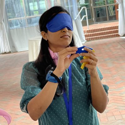 A participant in the Integrity team building event, blindfolded and carefully handling a challenge item, demonstrating focus and teamwork. thumbnail