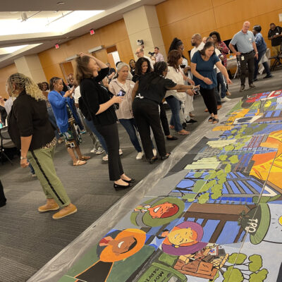 Participants gather to assemble their completed canvases into a large mural during The Big Picture team building event, showcasing their collaborative artwork and teamwork efforts. thumbnail