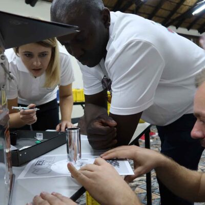Team members intensely focus on solving puzzles from a metal case during the 'Atmosphere' team building event, working together to unlock critical clues. thumbnail