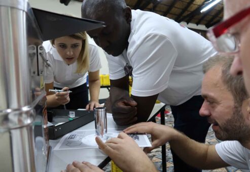 Team members intensely focus on solving puzzles from a metal case during the 'Atmosphere' team building event, working together to unlock critical clues.