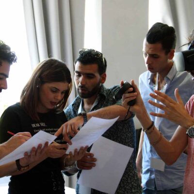 A group of participants collaborates on a task, with one member wearing a VR headset and explaining the virtual challenge to the rest of the team during The Infinite Loop team building event. thumbnail