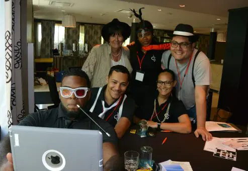 A team strikes a fun pose with an iPad during the Escape the Mob team building event, working together to solve the team building challenge.