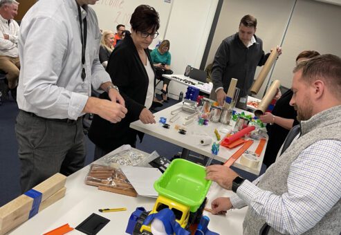 Participants engaged in the Domino Effect team building event, assembling creative contraptions using colorful materials.