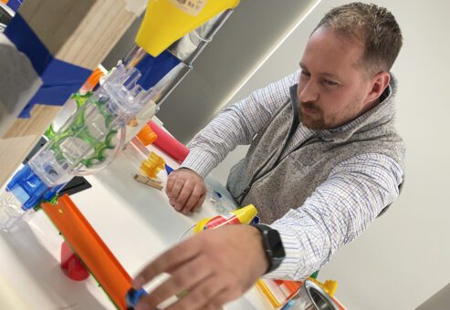 Participant working on a hands-on project during the Domino Effect team building event, focusing on creating Rube Goldberg-inspired contraptions to encourage creativity, problem-solving, and collaboration.