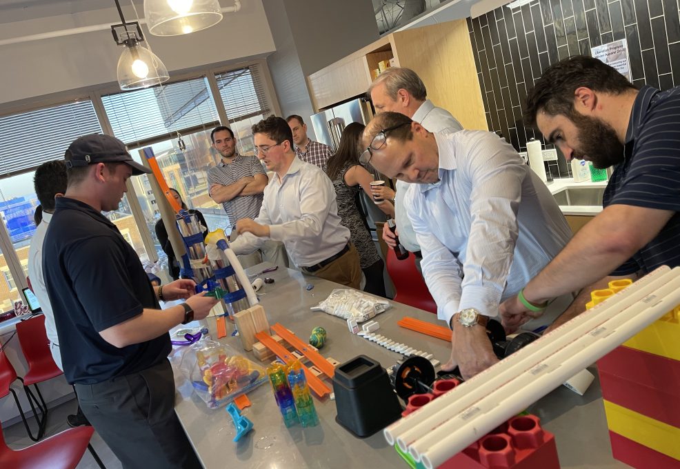 Participants at the Domino Effect team building event working together to complete a building challenge.