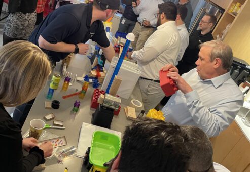 Group of participants collaborating and constructing complex devices during the Domino Effect team building event.