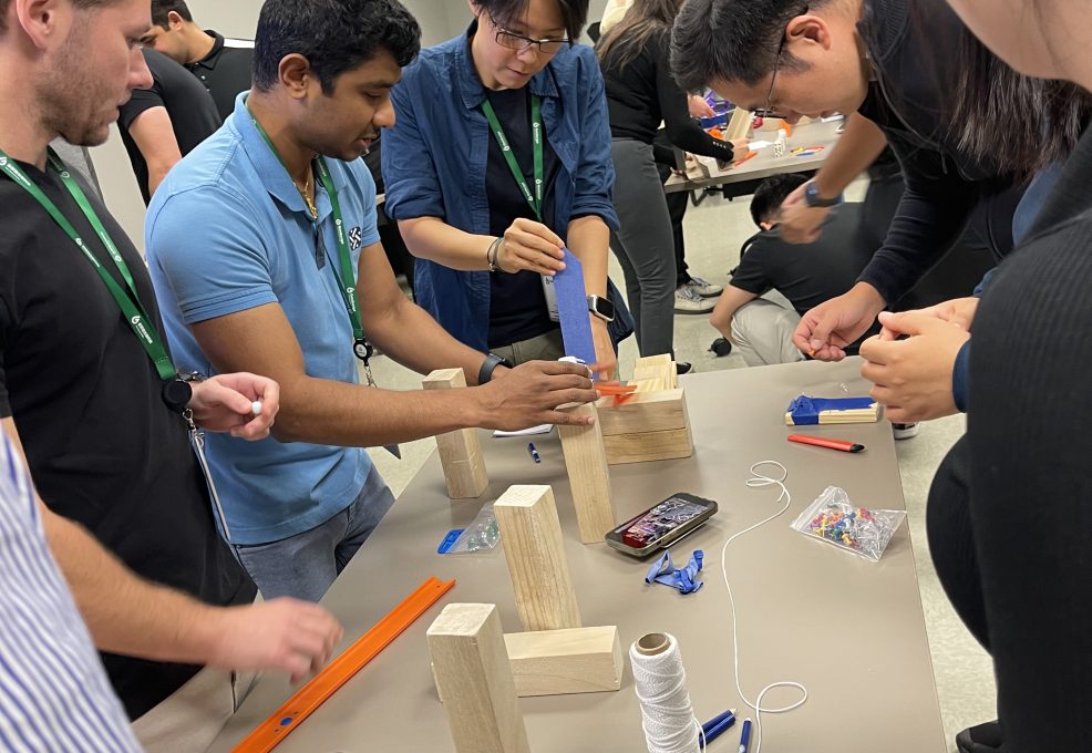 Team members working together on building a creative machine as part of the Domino Effect team building event.