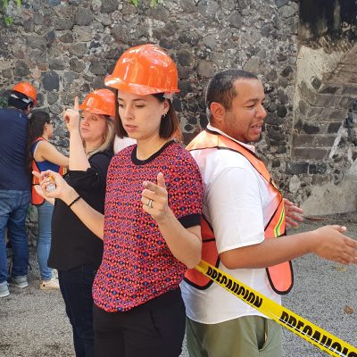 Outdoor team building activity focused on trust and communication. Paired participants wearing safety gear stand back-to-back, using non-verbal cues to complete the challenge, reinforcing teamwork and cooperation. thumbnail