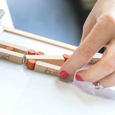 Close-up of a participant assembling an 'ibuild' model during a team building activity. The exercise emphasizes precision, communication, and collaboration to successfully recreate the structure. thumbnail