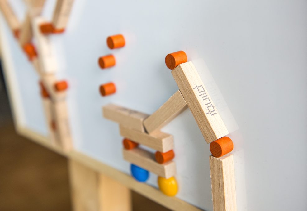 Close-up of an 'ibuild' model from a team building activity. Wooden pieces and connectors form a structure, highlighting the importance of precision, communication, and teamwork in the challenge.
