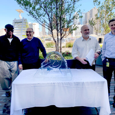 A group of participants proudly poses next to their completed ice sculpture, showcasing their teamwork and creativity during a Team building Ice Sculpting event. thumbnail