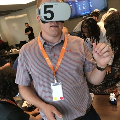 A participant wearing a VR headset labeled '5' engages in The Infinite Loop team building activity, immersing in a virtual reality experience during the event. thumbnail