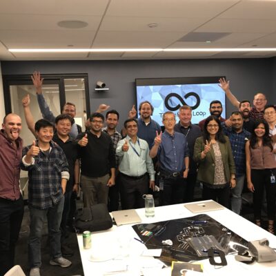 A group of participants enthusiastically pose with raised hands at the conclusion of The Infinite Loop team building event. thumbnail