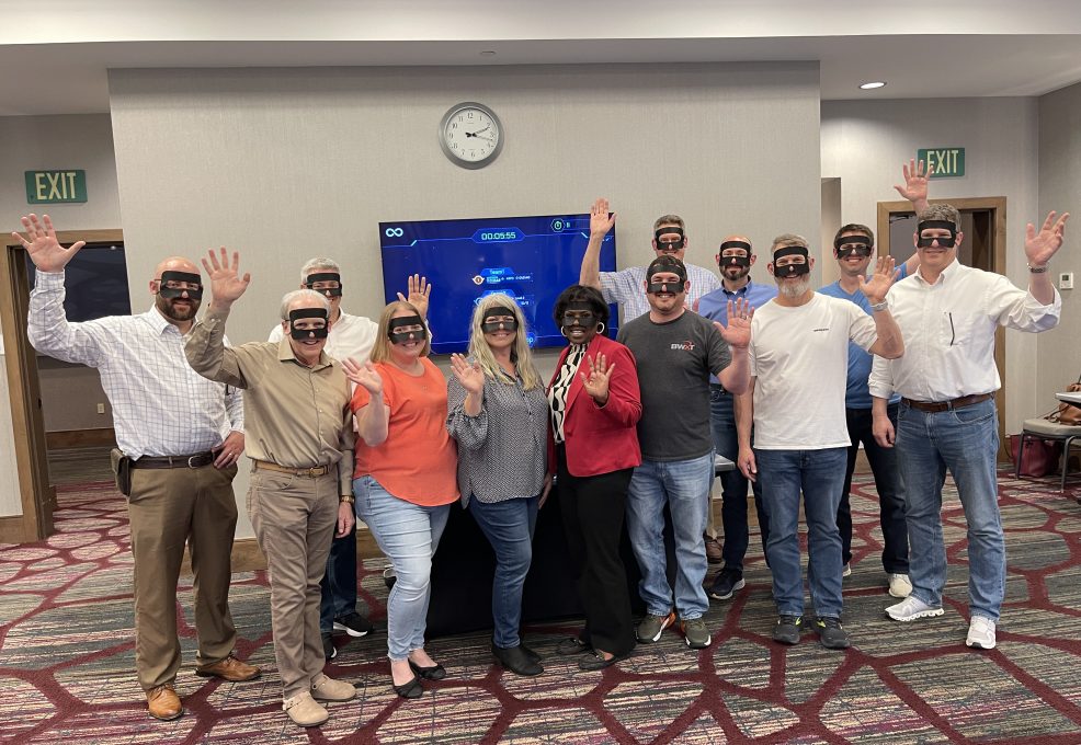 A group of participants pose for a group photo during The Infinite Loop team building event, wearing VR headsets after completing their collaborative virtual challenge.