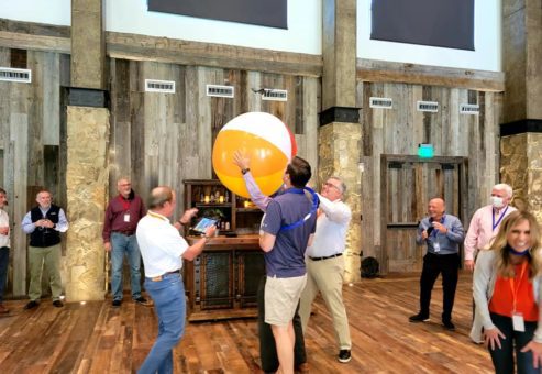 Participants work together to keep a giant beach ball in the air during a lively team building activity, fostering collaboration and fun.
