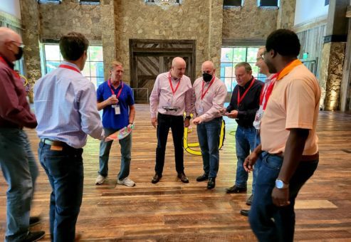 A group collaborates and strategizes during the Game of Drones team building event, working together to maneuver their drone through obstacles.