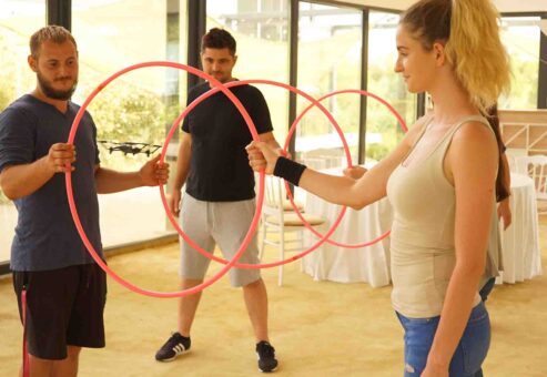 Team members focus on guiding a drone through a series of hoops during the Game of Drones team building event, promoting problem-solving and collaboration.