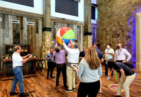 Team members collaborate to maneuver a large beach ball during the Game of Drones team building event, combining coordination and communication in a fun and dynamic environment.