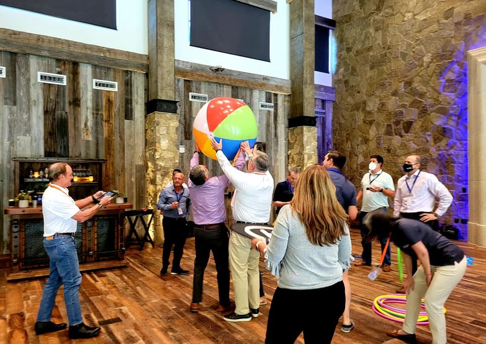 Team members collaborate to maneuver a large beach ball during the Game of Drones team building event, combining coordination and communication in a fun and dynamic environment.