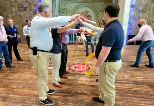 Participants work together to guide a drone through obstacles using teamwork and strategy during the Game of Drones team building event, fostering collaboration and problem-solving.