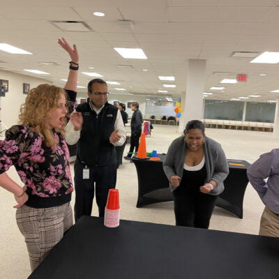 Participants enthusiastically reacting and cheering during a cup stacking challenge in the In It to Win It team building game, displaying excitement, competitive spirit, and teamwork. thumbnail