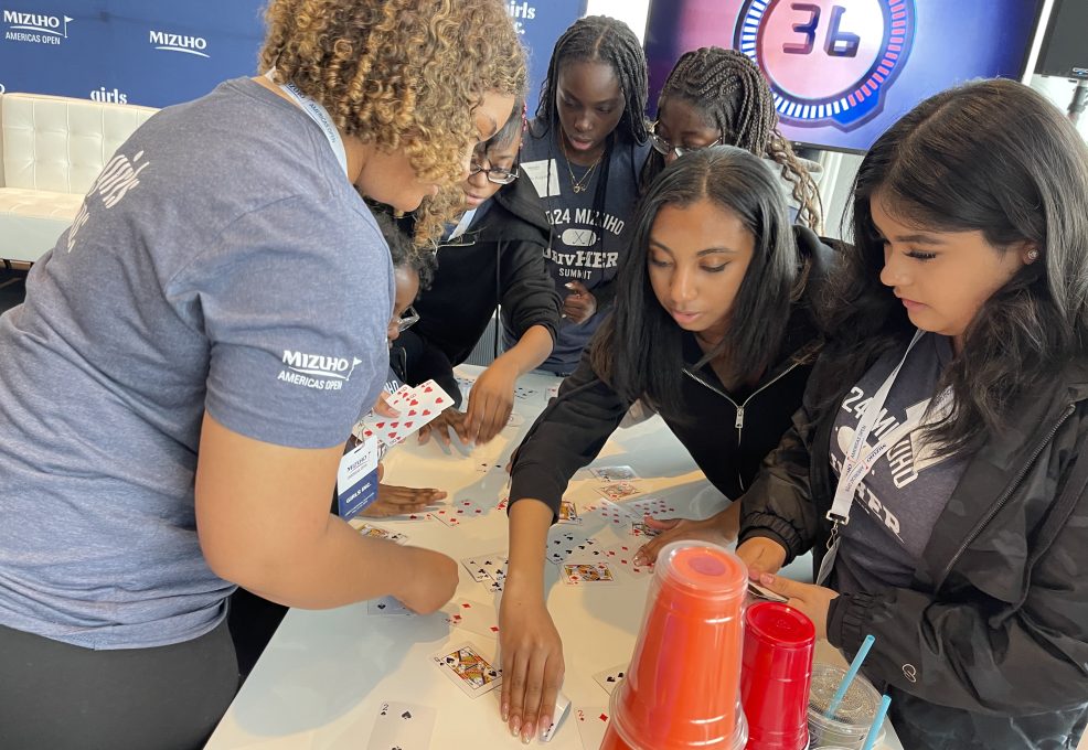 Participants focused on a card stacking challenge during In It to Win It, displaying teamwork, concentration, and quick thinking as they work together to complete the task within the 60-second time limit.
