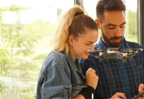 Two participants control a drone during the Game of Drones team building event, showcasing collaboration and hands-on technology.