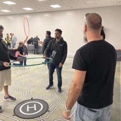 Team members strategize their next move while guiding a drone through an obstacle course during the Game of Drones team building event. thumbnail