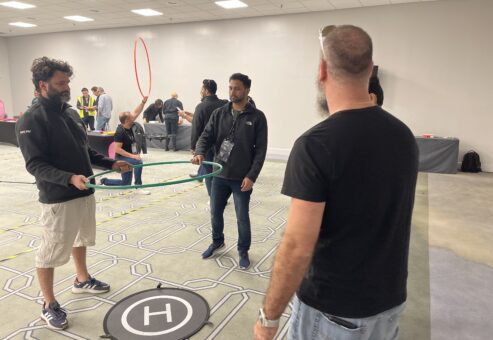 Team members strategize their next move while guiding a drone through an obstacle course during the Game of Drones team building event.
