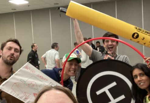 Team members pose with drone navigation tools and equipment after completing a successful round of the Game of Drones team building challenge.