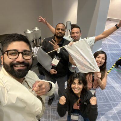 A team excitedly poses with their drone creation after completing a challenge during the Game of Drones team building event. thumbnail