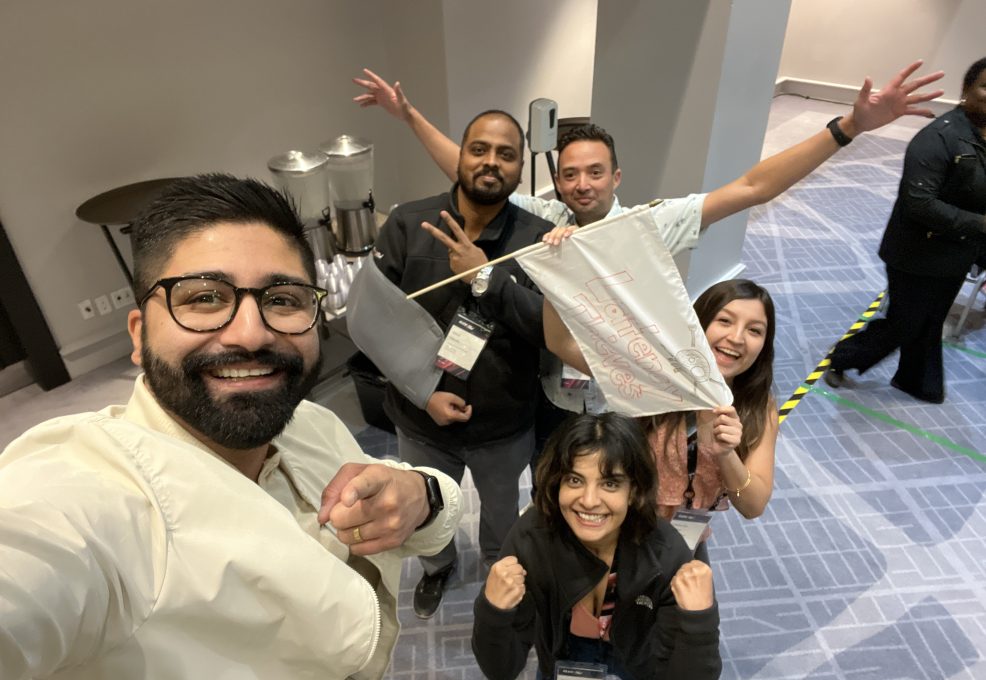A team excitedly poses with their drone creation after completing a challenge during the Game of Drones team building event.