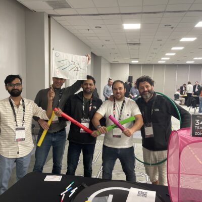 A team stands proudly with colorful drone navigation props during the Game of Drones team building event, ready to take on the challenges ahead. thumbnail