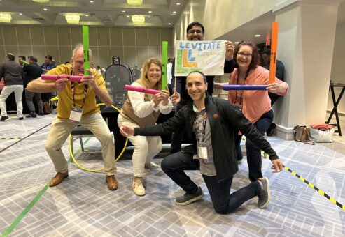 Team enthusiastically posing with colorful drone controllers during a high-energy Game of Drones team building event.