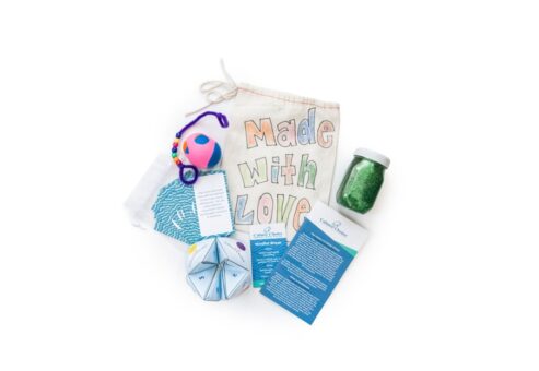 A collection of items including a Made with Love bag, a glitter jar, a colorful ball, and mindfulness cards.