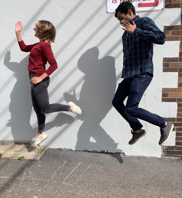 Two participants joyfully jumping in the air, creating playful shadows on a wall during the Healthcare Heroes scavenger hunt team building program.