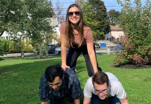 Three participants forming a human pyramid during the Healthcare Heroes scavenger hunt team building program.