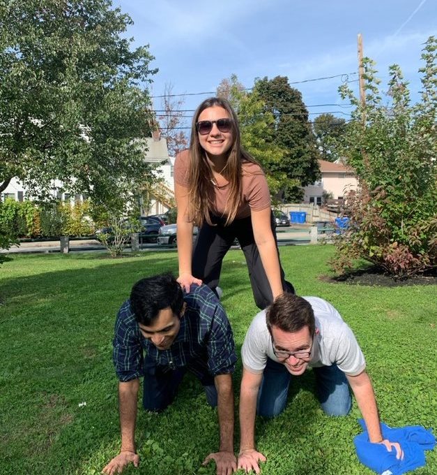 Three participants forming a human pyramid during the Healthcare Heroes scavenger hunt team building program.