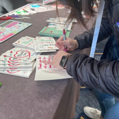 A participant writing heartfelt thank-you notes to healthcare workers during the Healthcare Heroes scavenger hunt team building activity. thumbnail