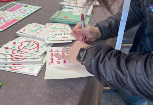 A participant writing heartfelt thank-you notes to healthcare workers during the Healthcare Heroes scavenger hunt team building activity.