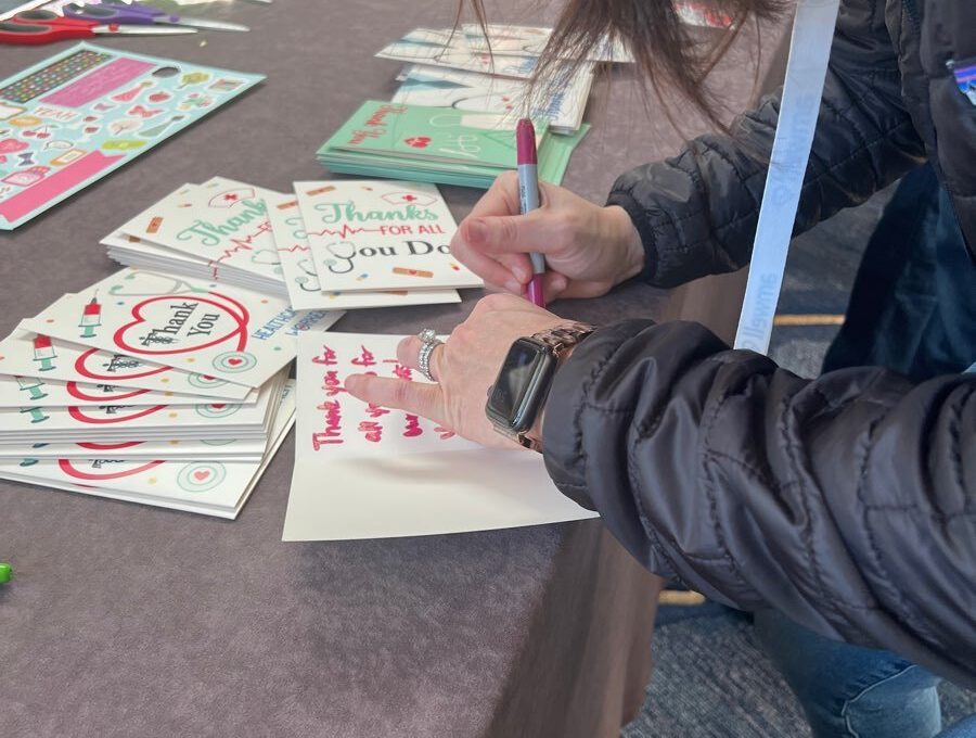 A participant writing heartfelt thank-you notes to healthcare workers during the Healthcare Heroes scavenger hunt team building activity.