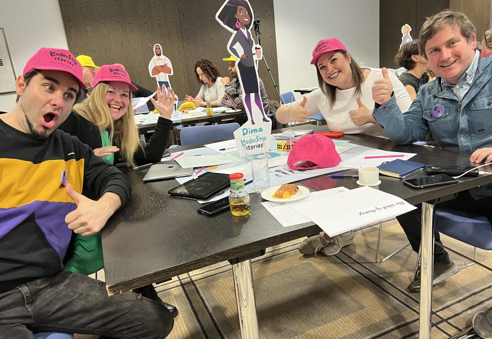 Team members having fun and posing with their game character cutouts during the Leadership Stories event.