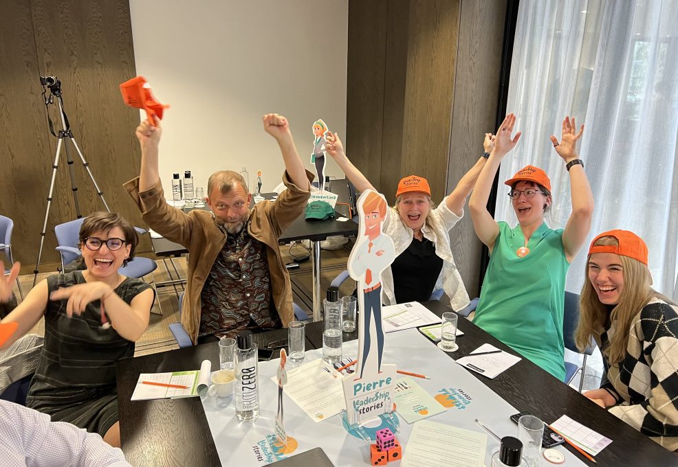 Team members celebrating and enjoying the Leadership Stories team building event, showcasing leadership skills in an engaging, board game-style competition.