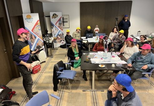 Team members actively participating in the Leadership Stories game, wearing colorful hats and engaging in discussions, creating a fun and interactive learning environment.