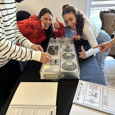 Excited participants smile and give thumbs up while engaging in a retro Team Synergy gaming challenge, focusing on teamwork and strategy. thumbnail