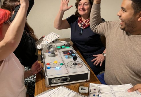 Excited participants high-five during the Team Synergy retro gaming team building activity, celebrating their success and teamwork around a game console.