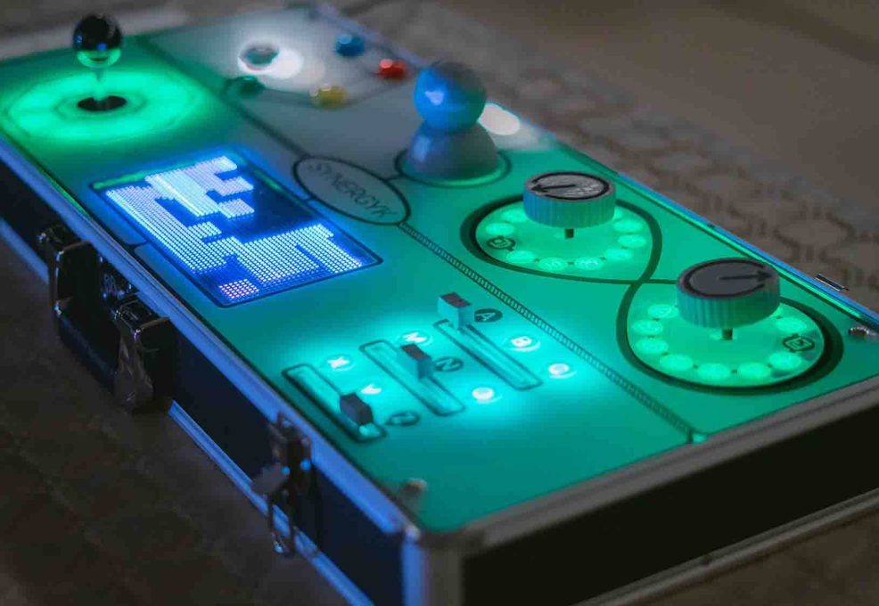 Close-up of a glowing Team Synergy retro gaming console with joysticks, buttons, and sliders, ready for a team building mini-game challenge.