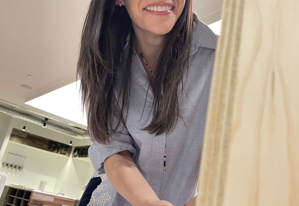 Participant smiling while using a power tool to assemble a Little Free Library during the Little Team Library team building event.